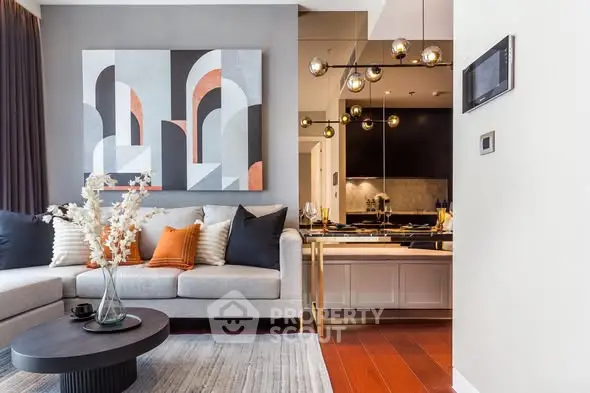 Modern living room with stylish decor and open kitchen layout, featuring elegant lighting and contemporary artwork.