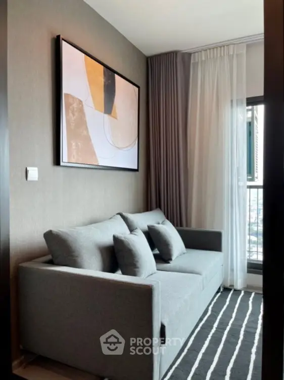 Modern living room with stylish gray sofa and abstract art, featuring floor-to-ceiling window for natural light.