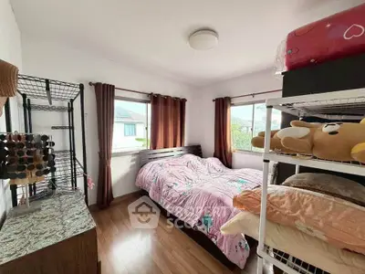Cozy bedroom with wooden flooring and ample natural light, featuring a comfortable bed and stylish decor.