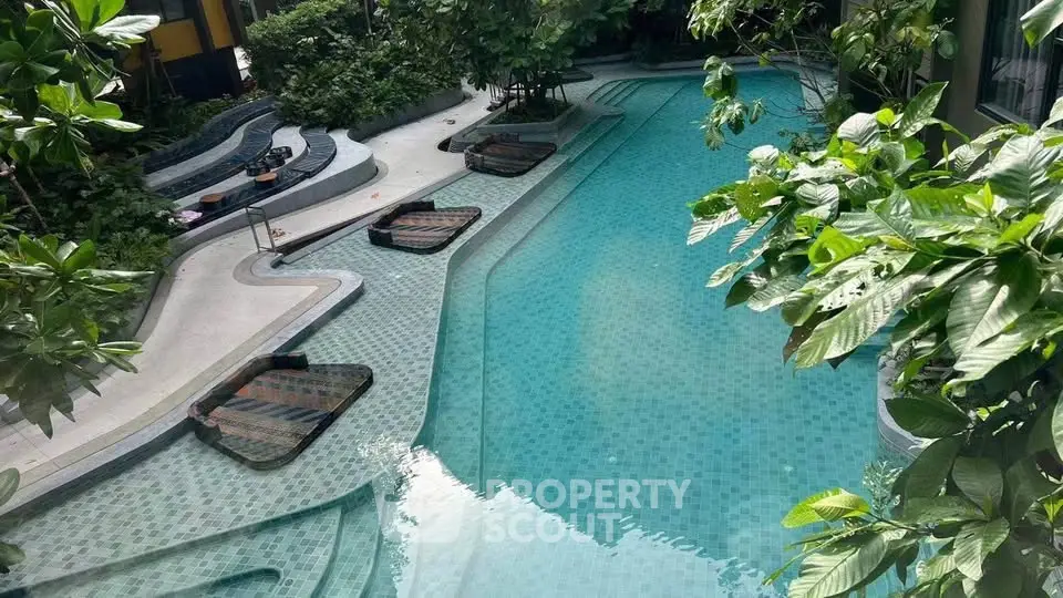 Luxurious outdoor pool with lush greenery and stylish lounge chairs in a serene setting.