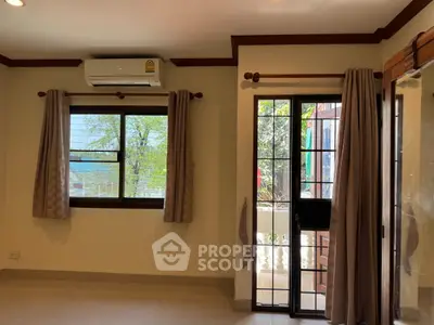 Bright living room with large windows and air conditioning, offering a view of the garden.