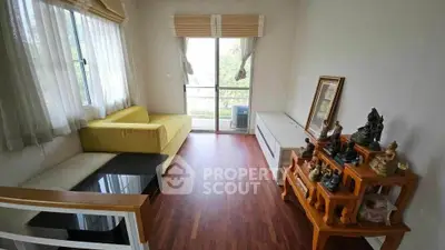 Bright living room with wooden flooring, yellow sofa, and decorative statues, offering a cozy and inviting atmosphere.