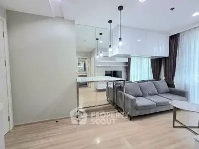 Modern living room with sleek design, featuring a cozy gray sofa, mirrored wall, and elegant lighting fixtures.