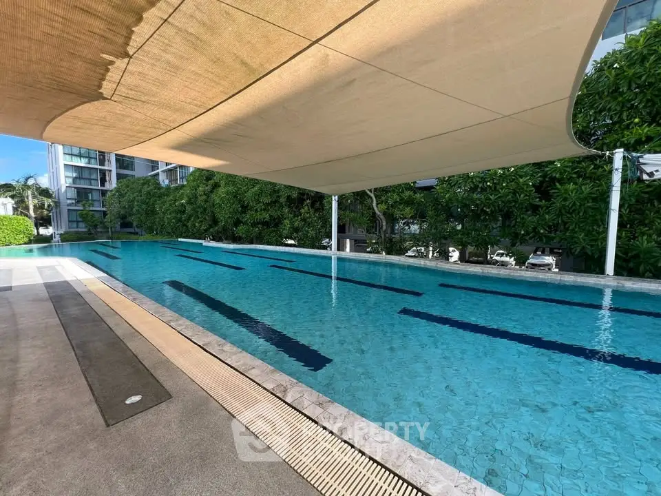 Luxurious outdoor pool with modern shade structure in upscale residential complex.