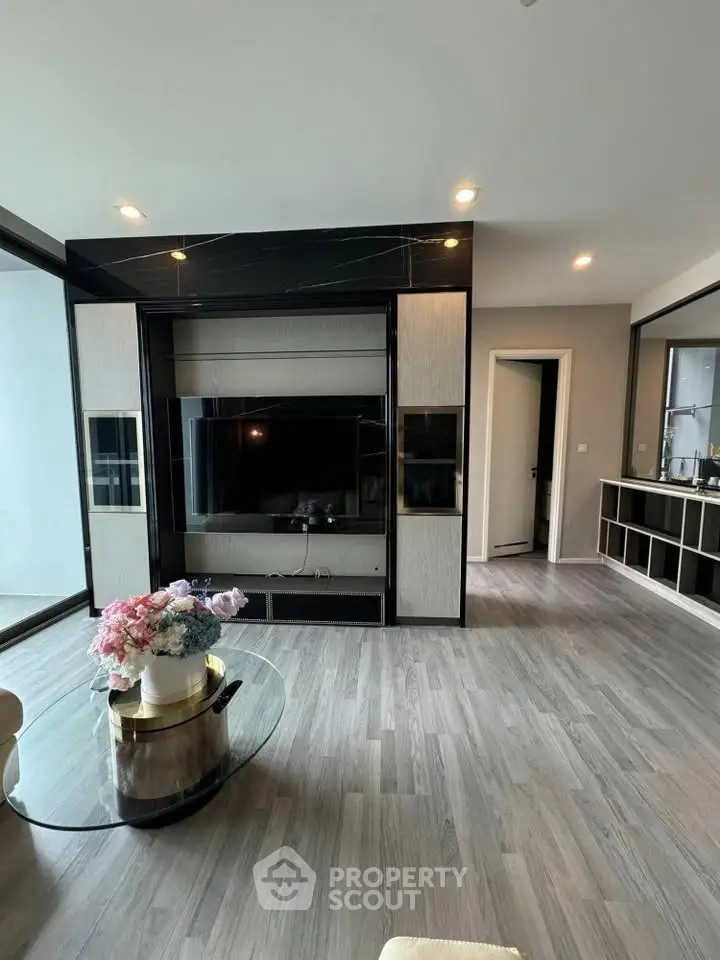 Modern living room with sleek TV unit and elegant decor, featuring large windows and stylish flooring.