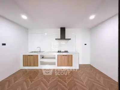 Modern minimalist kitchen with wooden cabinets and gas stove in a sleek open layout.