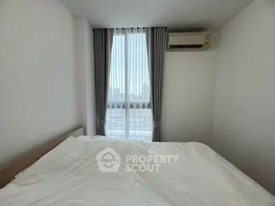 Bright bedroom with large window and air conditioning, offering a serene city view.