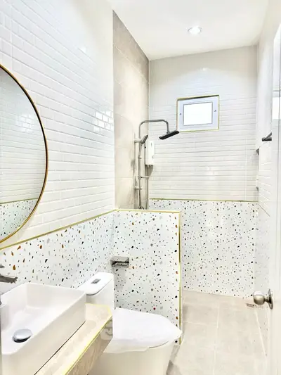 Modern bathroom with stylish terrazzo tiles and sleek fixtures, featuring a round mirror and compact design.