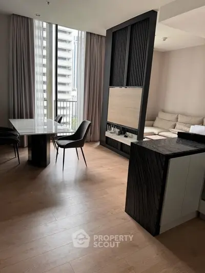 Modern open-plan living room with elegant dining area and large windows in a high-rise apartment.