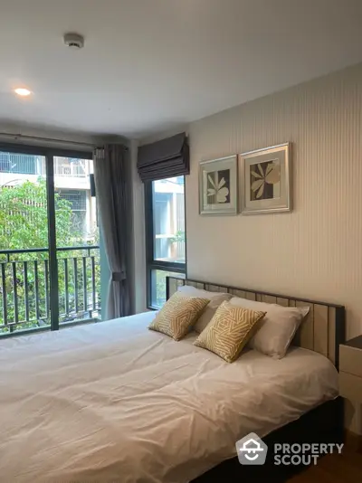 Serene bedroom with a comfortable queen-size bed, stylish wall art, and access to a private balcony overlooking lush greenery, perfect for restful nights and tranquil mornings.