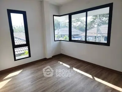 Bright empty room with large windows and wooden flooring, perfect for customization.
