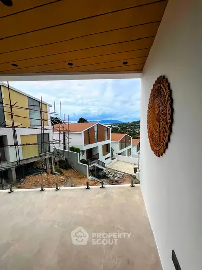 Modern balcony with scenic view of under-construction houses and mountains.
