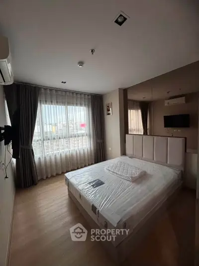 Modern bedroom with large window and city view, featuring a comfortable bed and stylish decor.