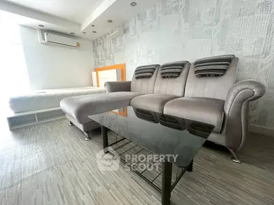 Modern living room with stylish gray sofa and glass coffee table, featuring sleek flooring and contemporary decor.