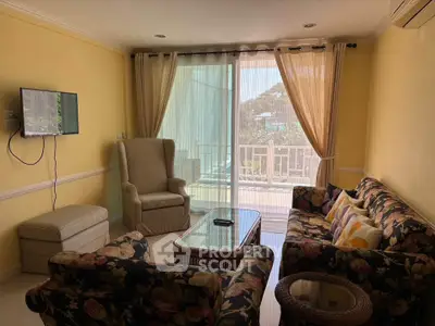 Cozy living room with floral sofas and balcony view, perfect for relaxation.