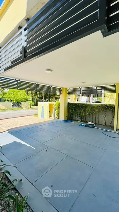 Spacious covered patio with modern design and lush greenery, perfect for outdoor relaxation.