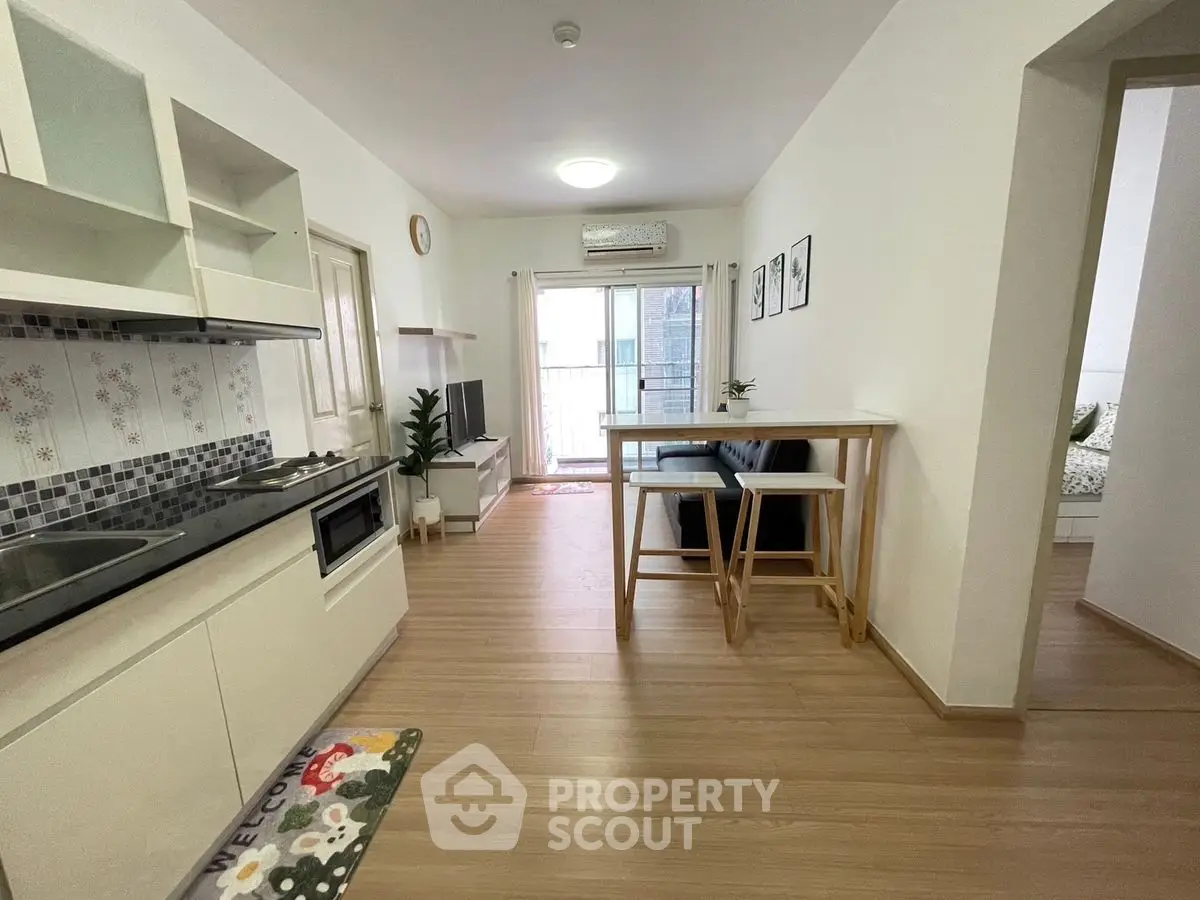 Modern open-layout kitchen and living area with wooden flooring and natural light.