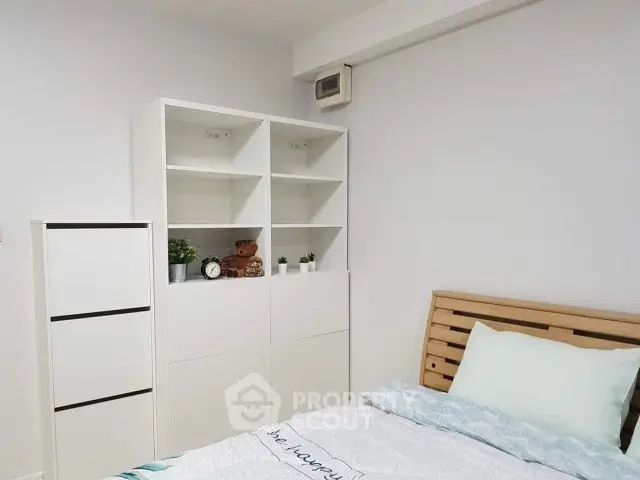 Cozy bedroom with modern shelving and wooden bed frame, perfect for a serene retreat.