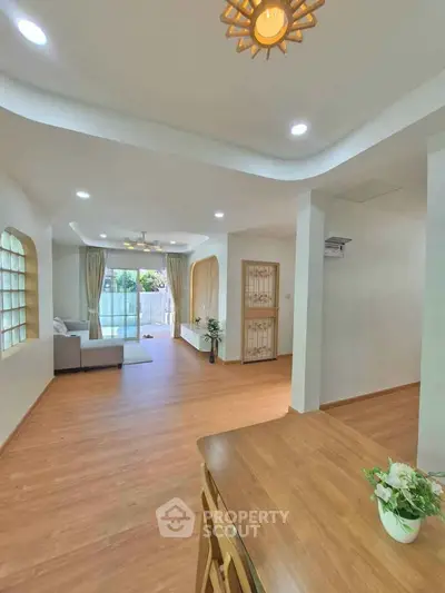Spacious living room with wooden flooring and large windows for natural light.