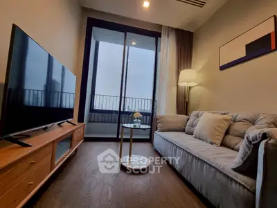 Modern living room with sleek furniture and large TV, opening to a balcony with a view.