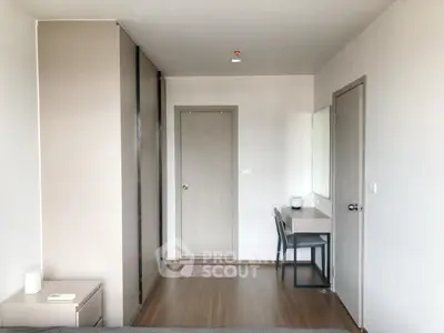Modern minimalist bedroom with sleek furniture and neutral tones, featuring a study desk and ample storage space.
