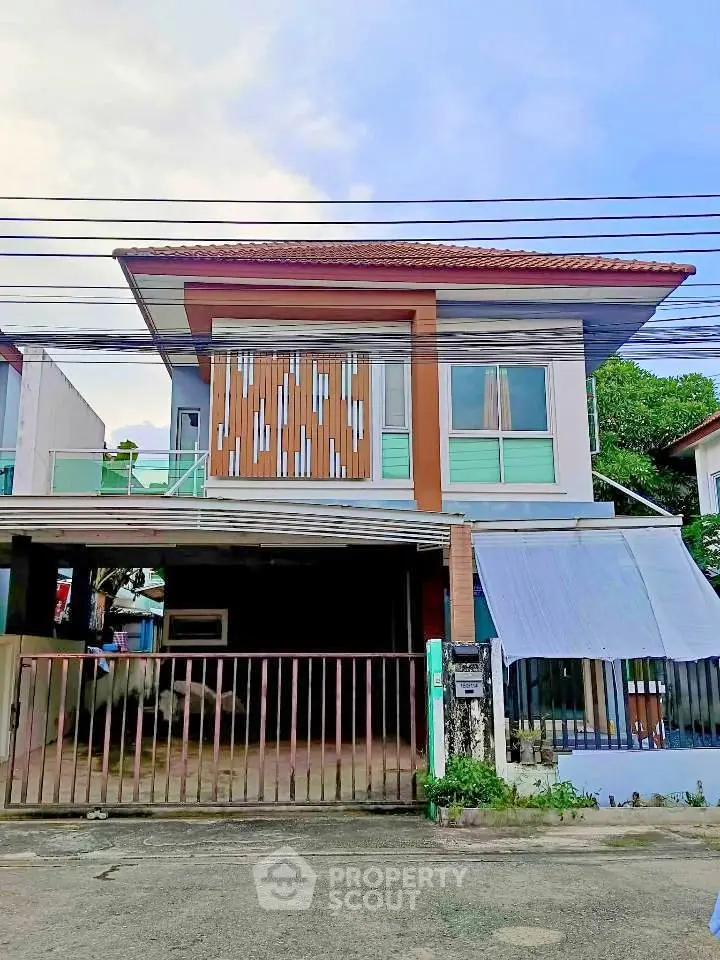 Modern two-story house with unique facade and gated entrance in suburban neighborhood.
