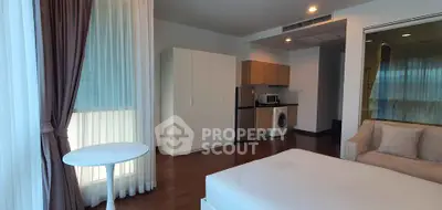 Modern studio apartment with open layout, featuring a cozy living area, kitchenette, and washing machine.