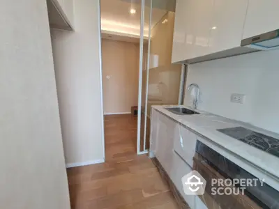 Modern kitchen with sleek cabinetry and hardwood floors in a contemporary apartment.