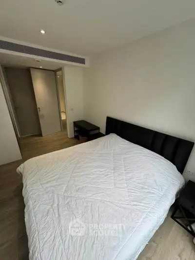 Modern bedroom with minimalist design and cozy atmosphere, featuring a comfortable bed and sleek furnishings.