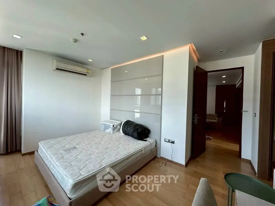 Spacious bedroom with wooden flooring and modern air conditioning unit, perfect for comfort and relaxation.
