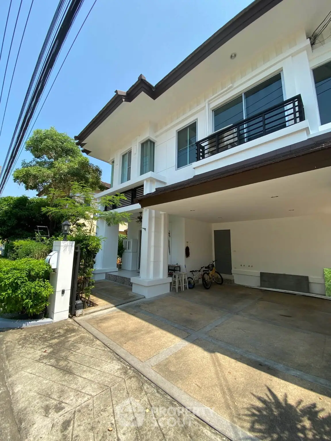 Modern two-story house with spacious driveway and lush greenery, perfect for family living.