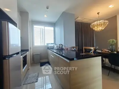 Modern kitchen with sleek design and elegant dining area featuring a stunning chandelier.