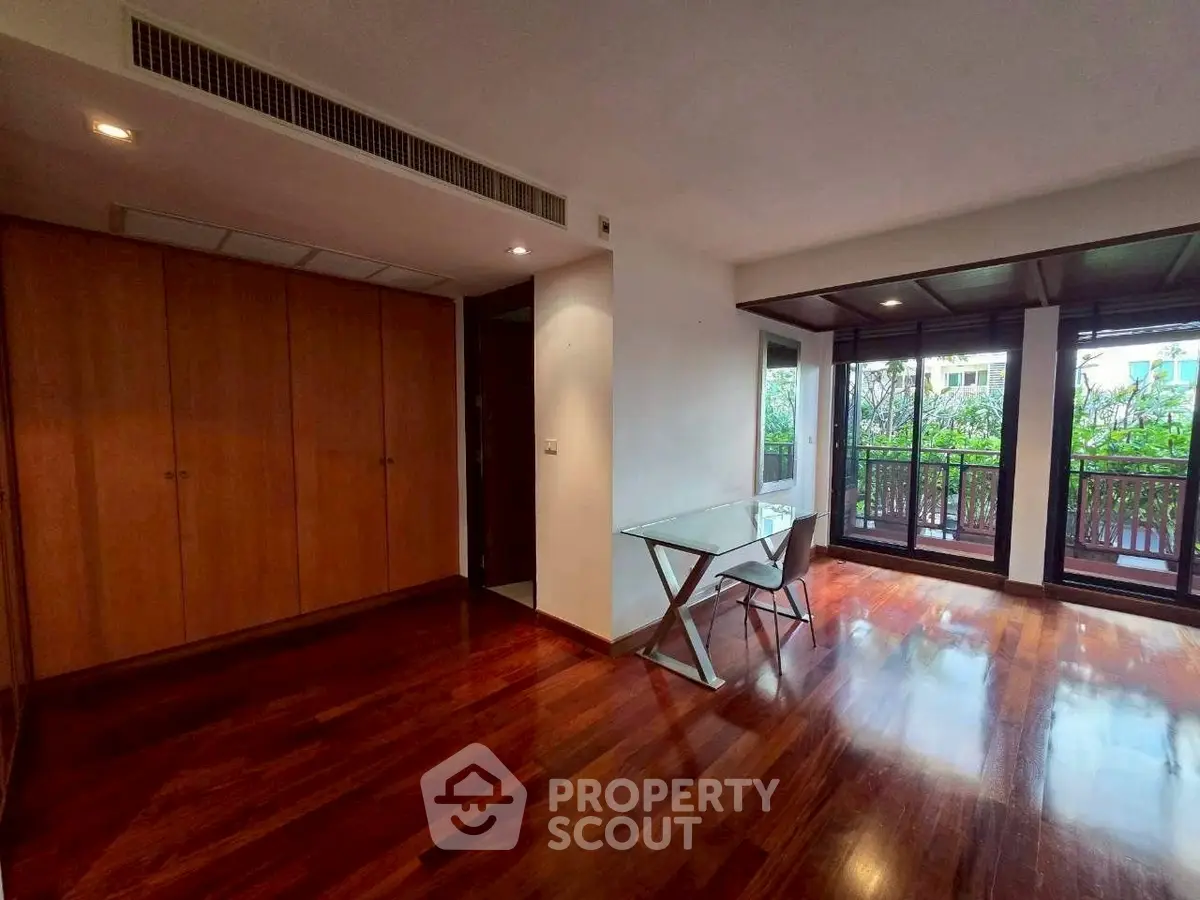 Spacious room with wooden floors and balcony view, perfect for modern living.