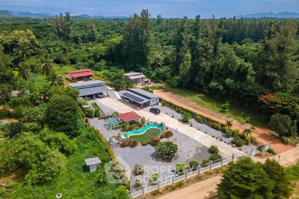 Stunning aerial view of a countryside property with lush greenery and a private pool, perfect for serene living.