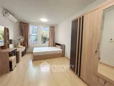 Spacious bedroom with modern wooden furniture and large windows for natural light