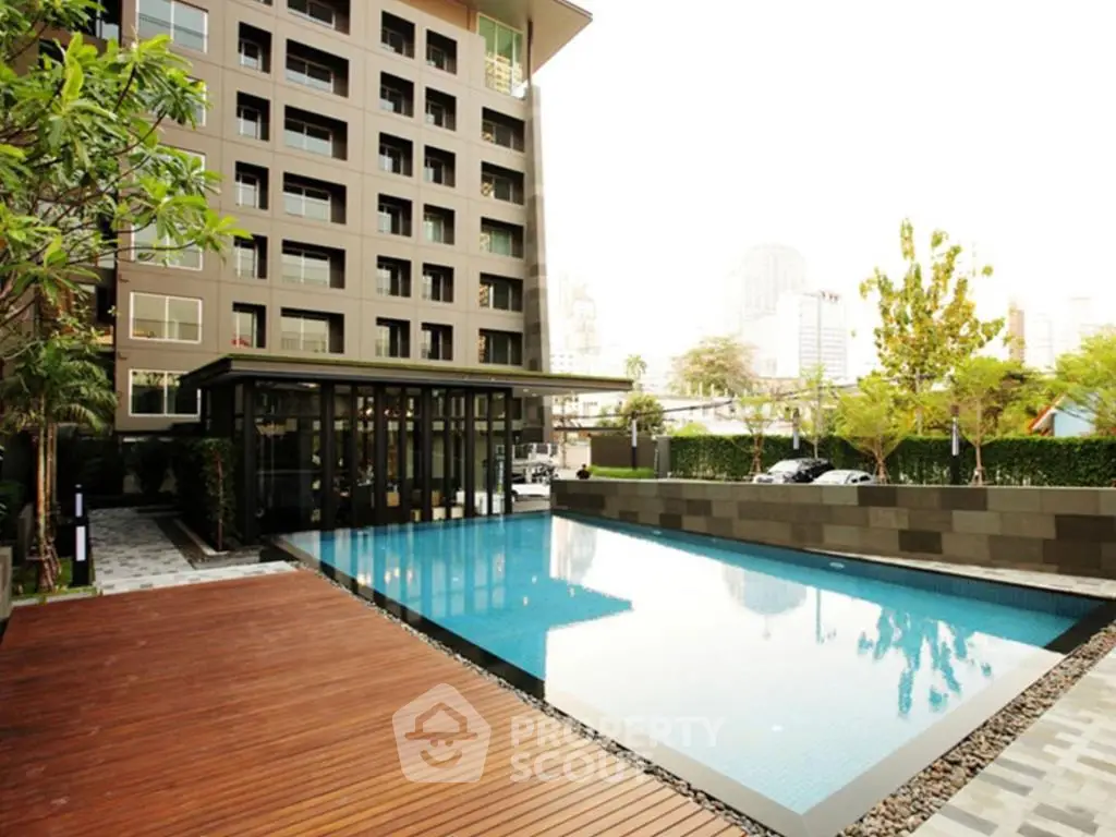 Luxurious apartment complex with modern pool and wooden deck, perfect for relaxation.