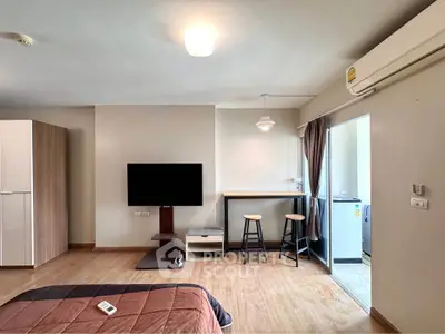 Modern studio apartment with cozy bedroom and open living area featuring TV and bar seating.