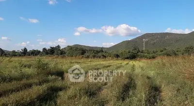 Expansive green field with scenic mountain backdrop, perfect for development opportunities.