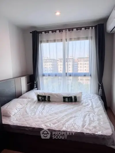 Cozy bedroom with large window and modern decor in urban apartment.