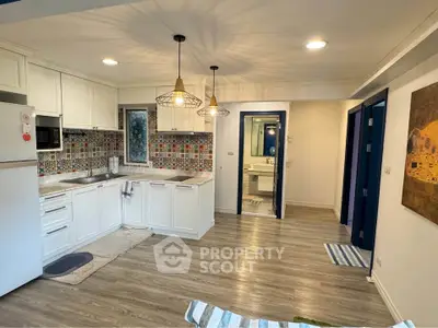 Charming open-layout kitchen with colorful backsplash and modern lighting in a cozy apartment.