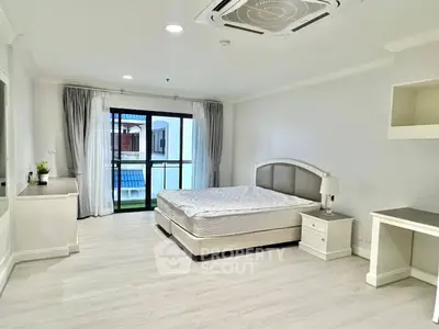 Spacious bedroom with modern furnishings and balcony access in a luxury apartment.