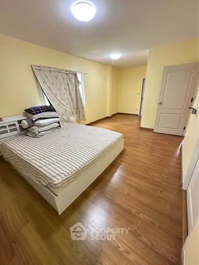 Spacious bedroom with wooden flooring and cozy bed setup