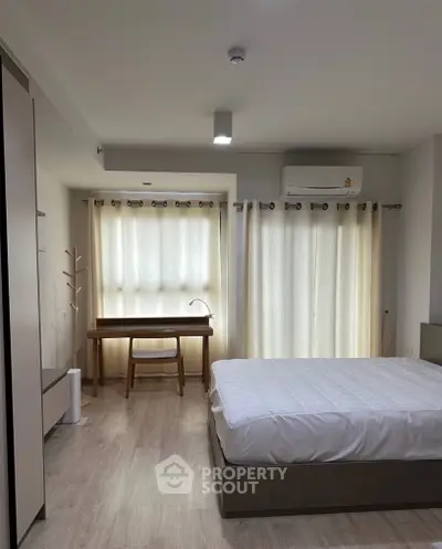 Modern bedroom with natural light, featuring a cozy bed and a stylish work desk.