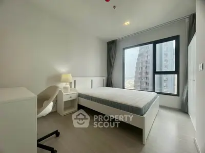 Modern bedroom with large window and city view, featuring a comfortable bed and stylish furniture.