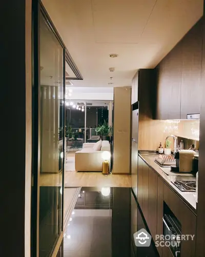 Sleek modern kitchen with high-gloss cabinetry and integrated appliances flows into a cozy living area, showcasing a seamless open layout perfect for entertaining.