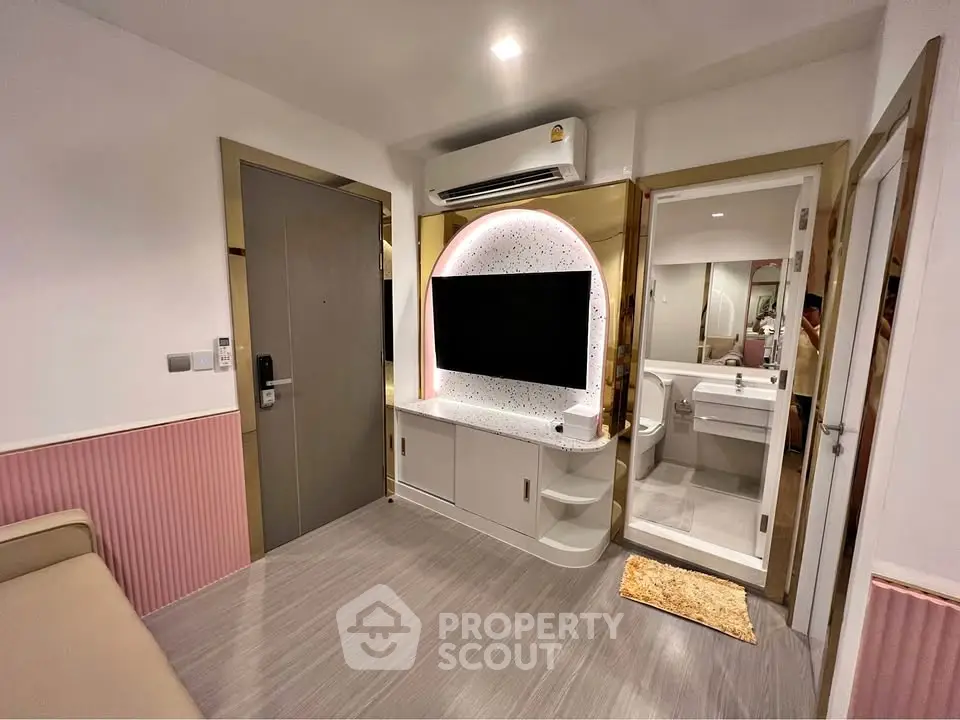 Modern living room with stylish TV setup and adjacent bathroom in a cozy apartment.