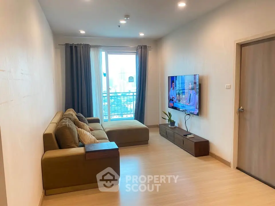 Modern living room with cozy sofa and wall-mounted TV, featuring a city view through large windows.