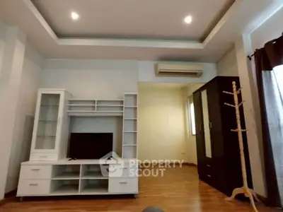 Spacious living room with modern furniture and wooden flooring, featuring ample storage and natural light.