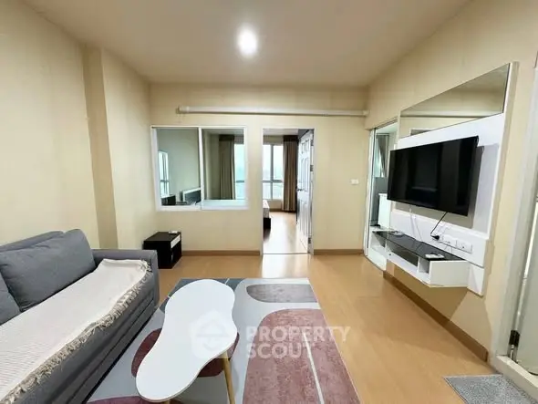 Modern living room with stylish furniture and wall-mounted TV in cozy apartment.