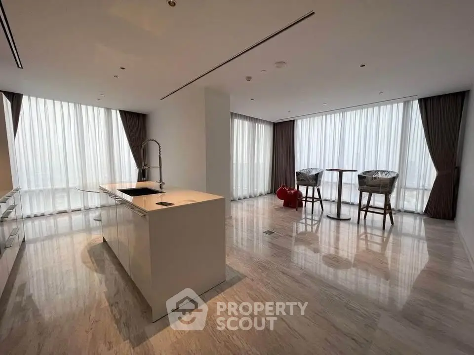 Spacious modern living room with open kitchen and large windows offering abundant natural light.